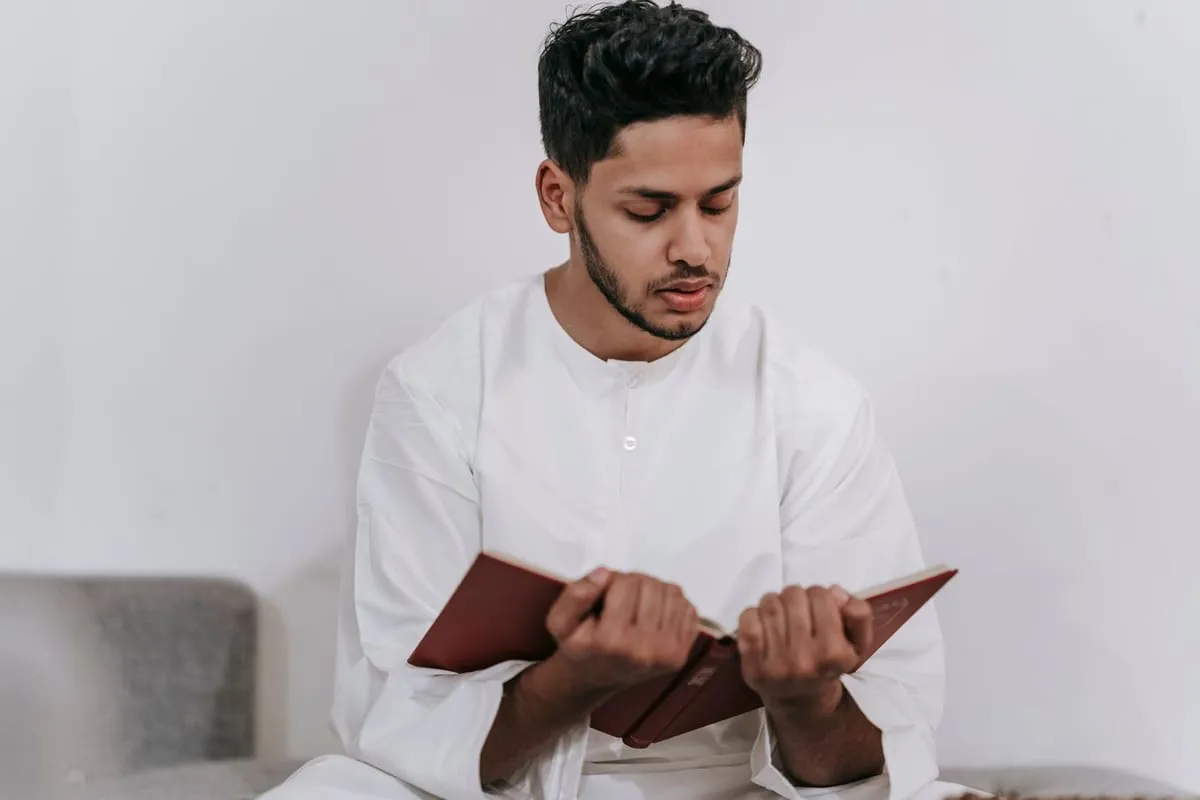 A young man in white reading the Quran