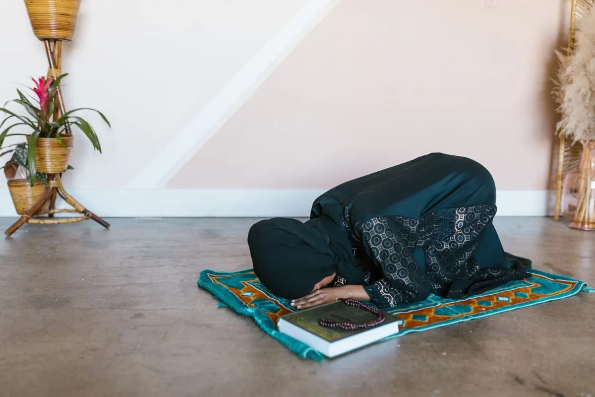 A person in prostration on a prayer mat