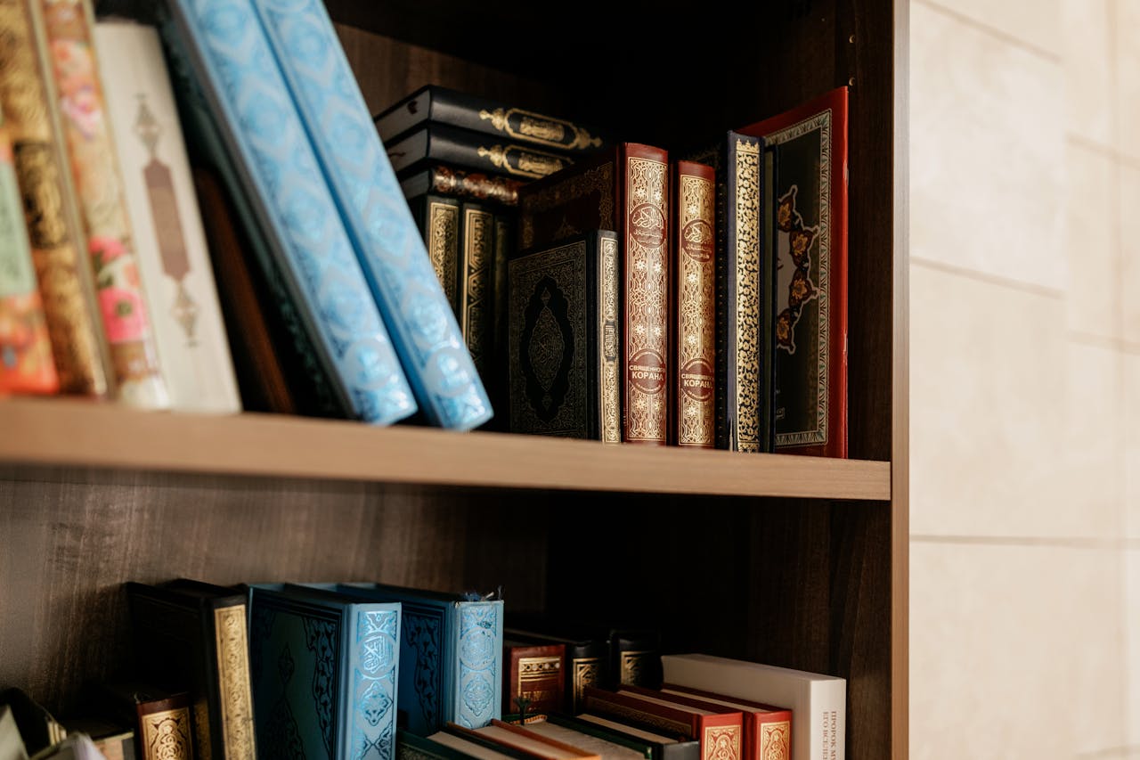 Close-up of decorative Islamic books on a wooden shelf, showcasing intricate bindings.